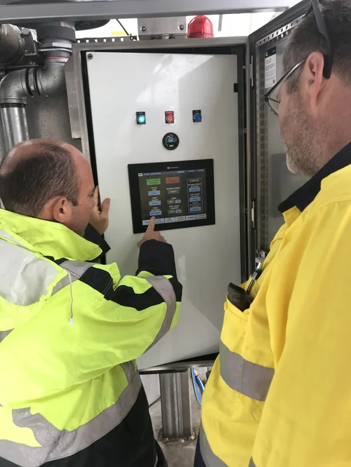 Two ST8 Wide electricians inspecting an industrial control panel with touchscreen HMI