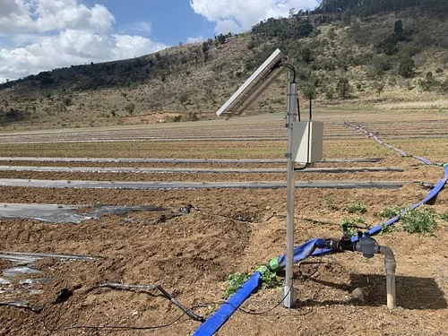 Solar panel installed in an agricultural field with irrigation pipes and a control box